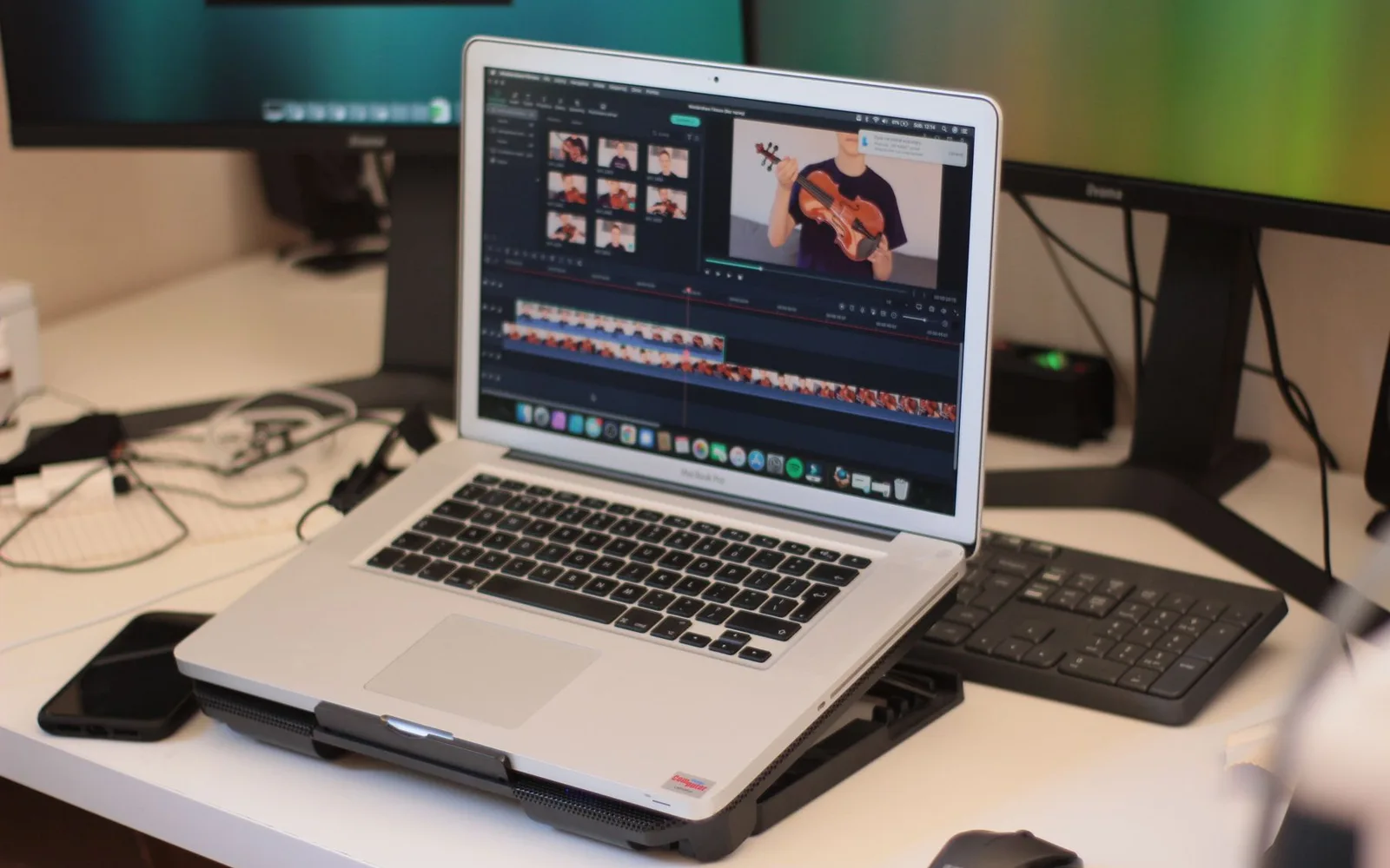 A laptop showing a video editing timeline on a desk