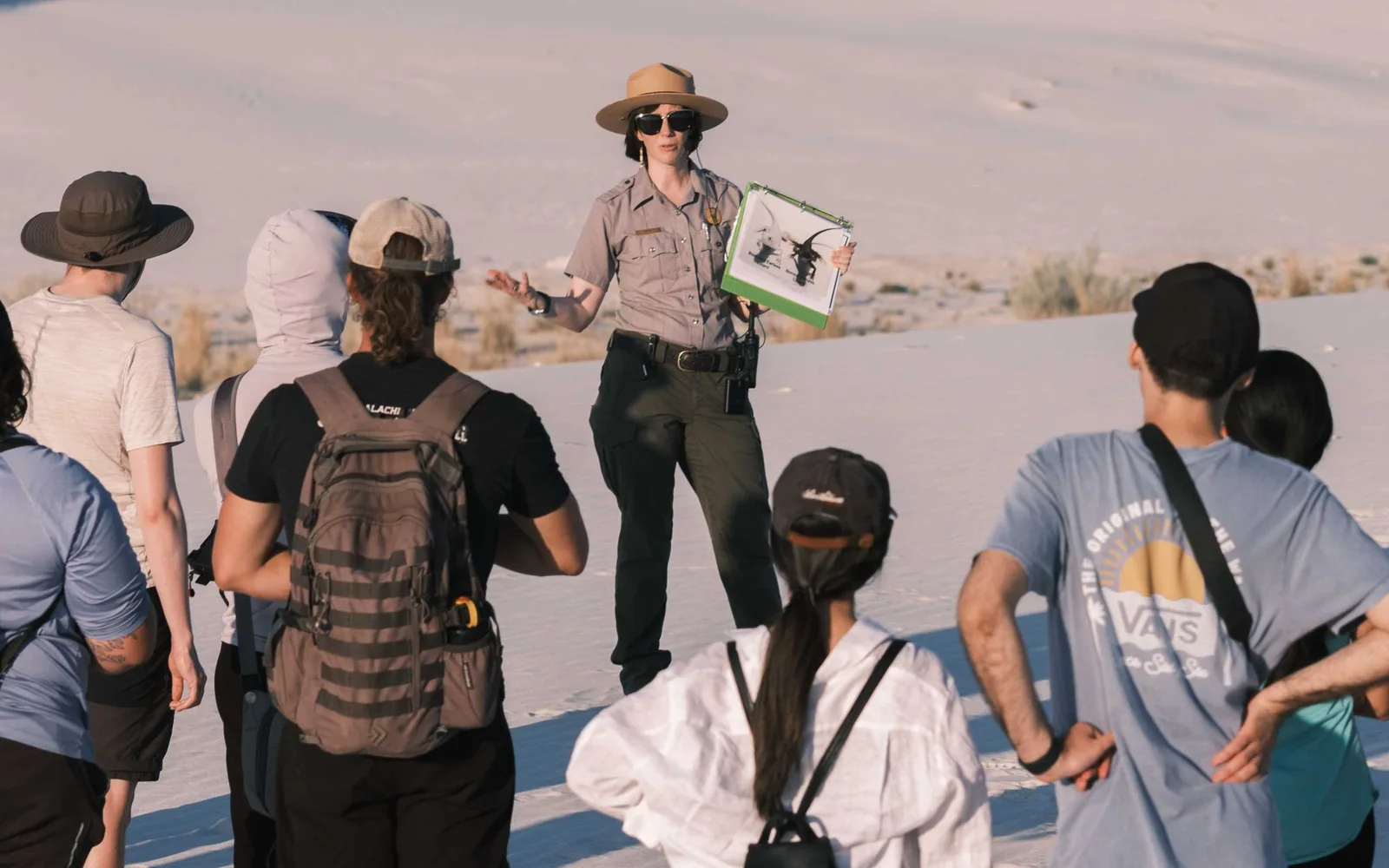 A park ranger addressing a group of visitors among sand dunes