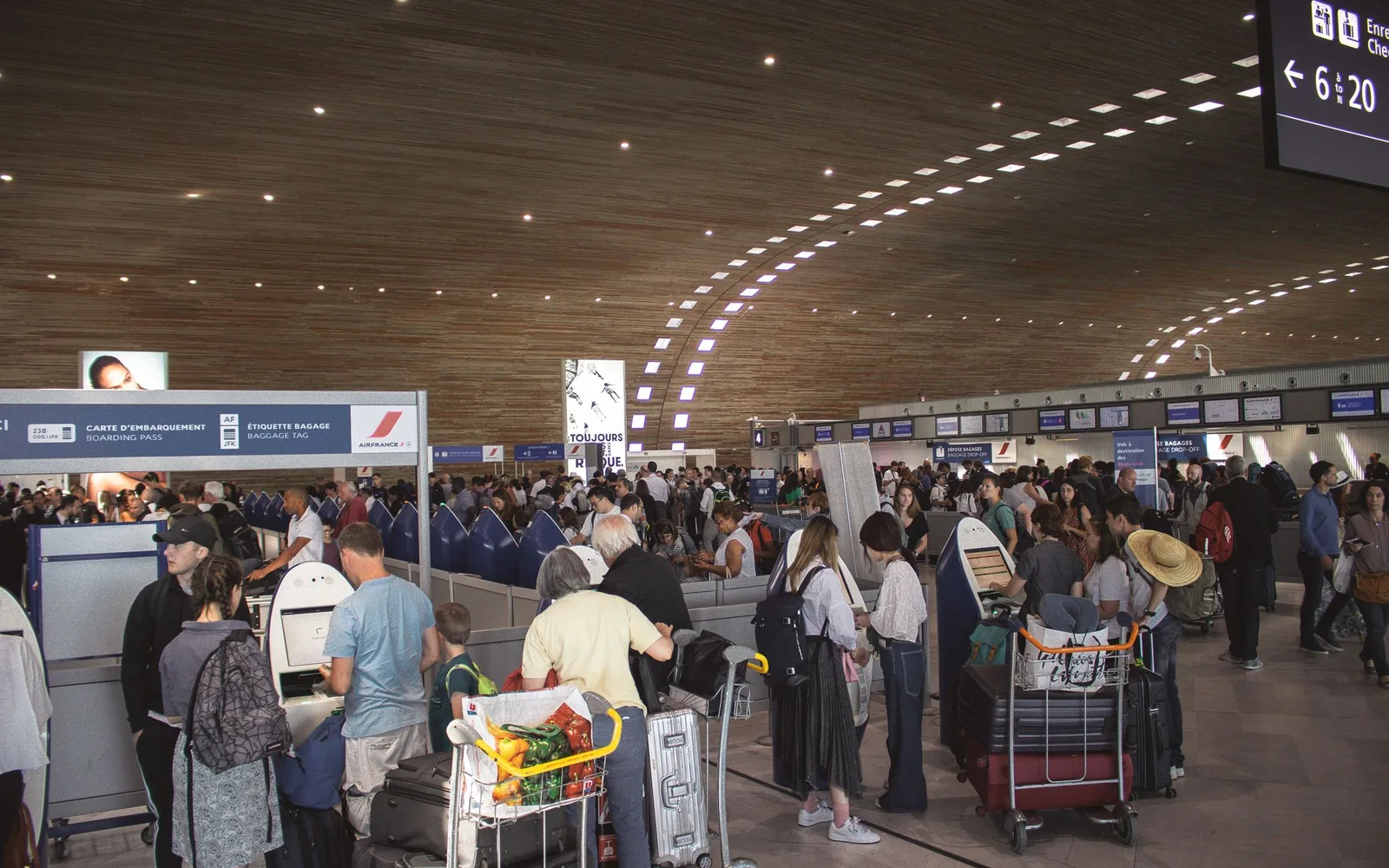 Travelers queuing with luggage inside a crowded airport terminal