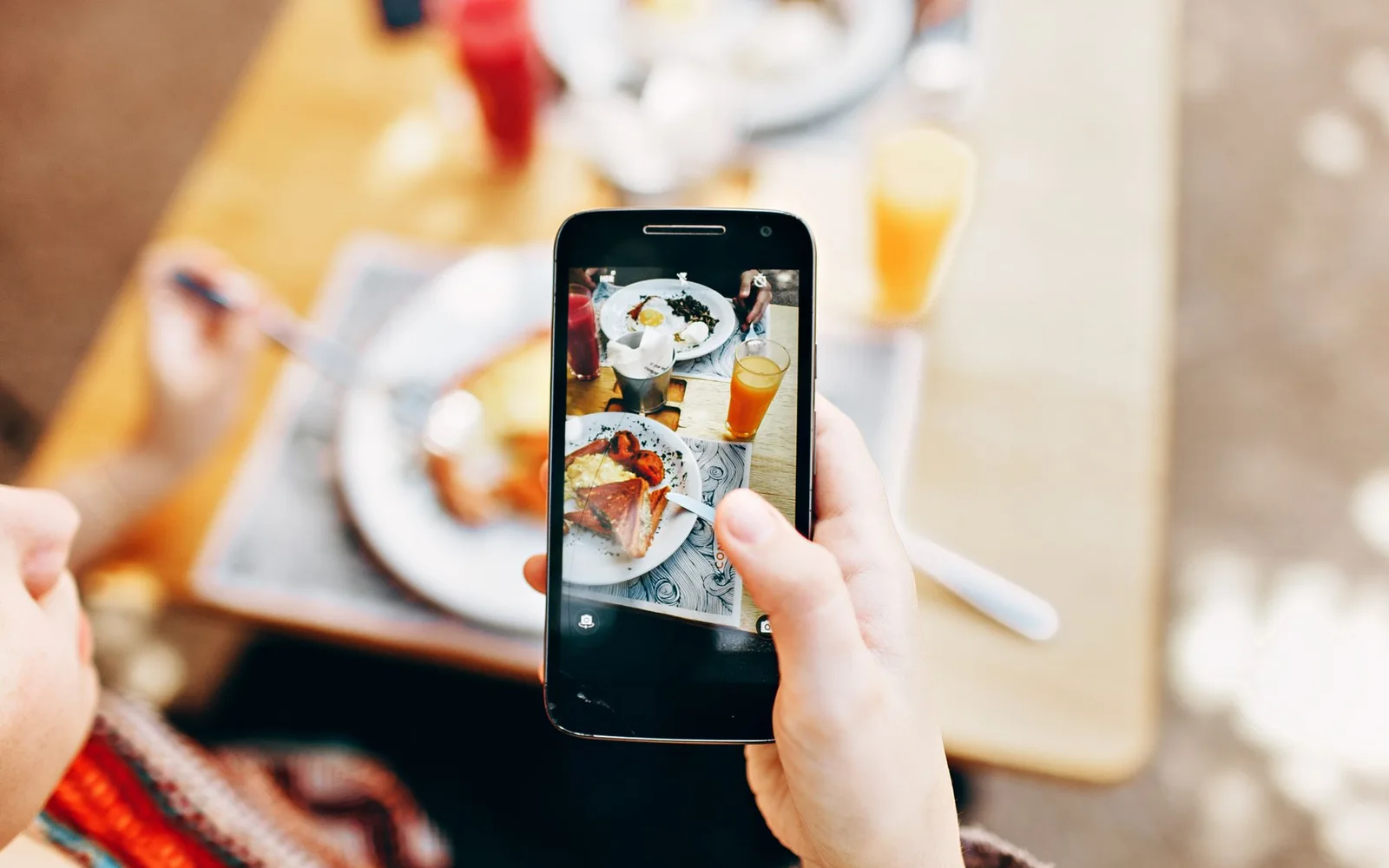 A person photographing a plated meal with a smartphone